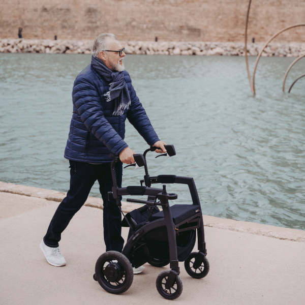 Homme senior marchant en extérieur avec le rollator Rollz Motion Electric, une aide à la mobilité transformable en fauteuil roulant électrique, confortable et sécurisé.