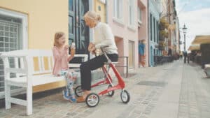 Homme senior élégant marchant en ville avec le rollator Carbon Ultralight noir de byACRE, le déambulateur le plus léger du monde, texture fibre de carbone visible.